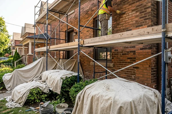 Drop cloths over garden beds below scaffolding during tuckpointing