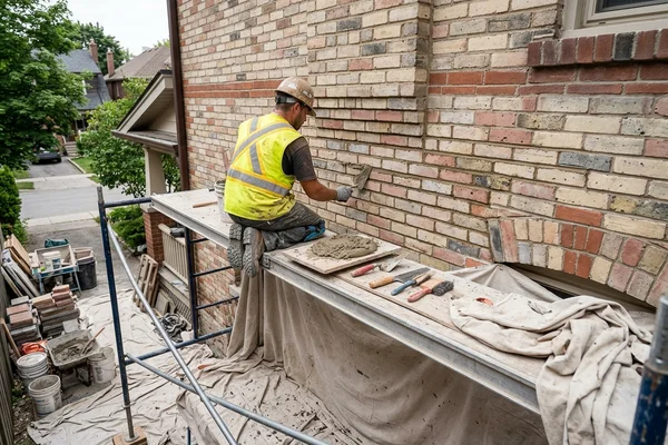 Mason packing fresh mortar into raked joints