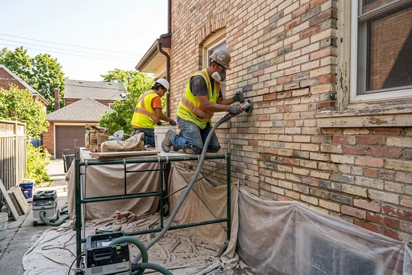 Mason raking out mortar joints with HEPA dust extraction