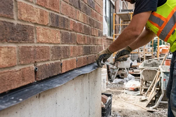 Through-wall flashing and weep holes at the base of new brick veneer